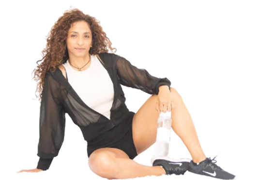 Mujer con ropa deportiva sentada en el suelo, en pose relajada tras entrenar, fondo blanco.